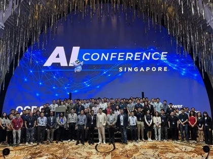 Conference attendees gathered on stage for a group photo under the AI Conference Singapore screen