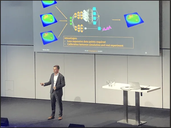 Kevin Cremanns presenting on stage at the CADFEM Conference 2024, with a slide showing a machine learning architecture and the advantages of needing fewer expensive data points and calibrating simulation against real experiments.
