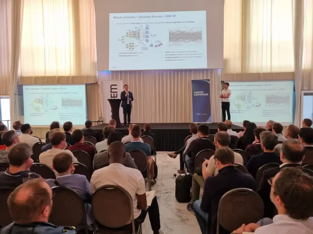 Two speakers presenting a slide reading Neural networks + Gaussian Process = DIM-GP to a full audience at the CADFEM Conference France 2025