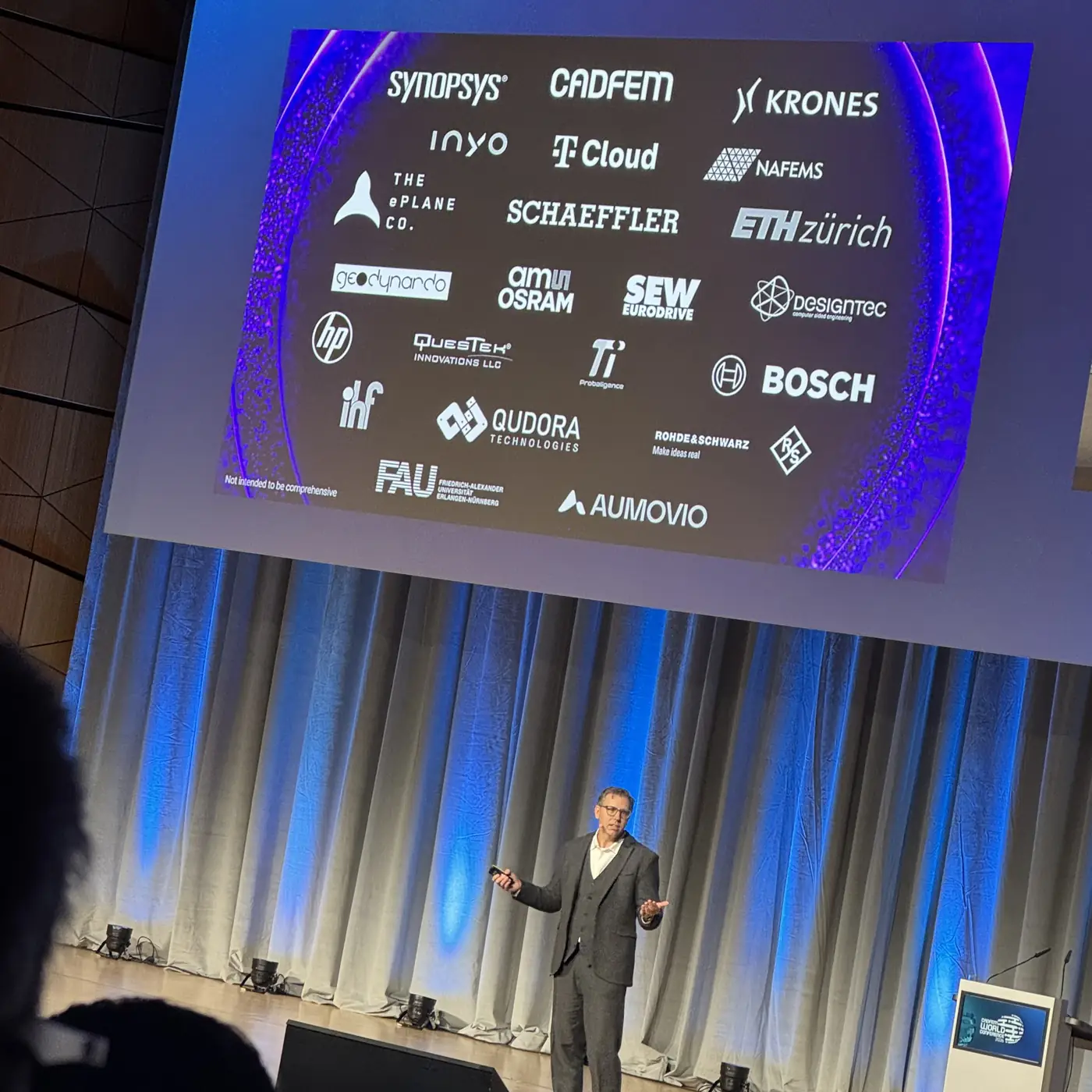 The closing keynote: a speaker under a slide with the logos of about 20 companies and universities at the conference, PI Probaligence among them.