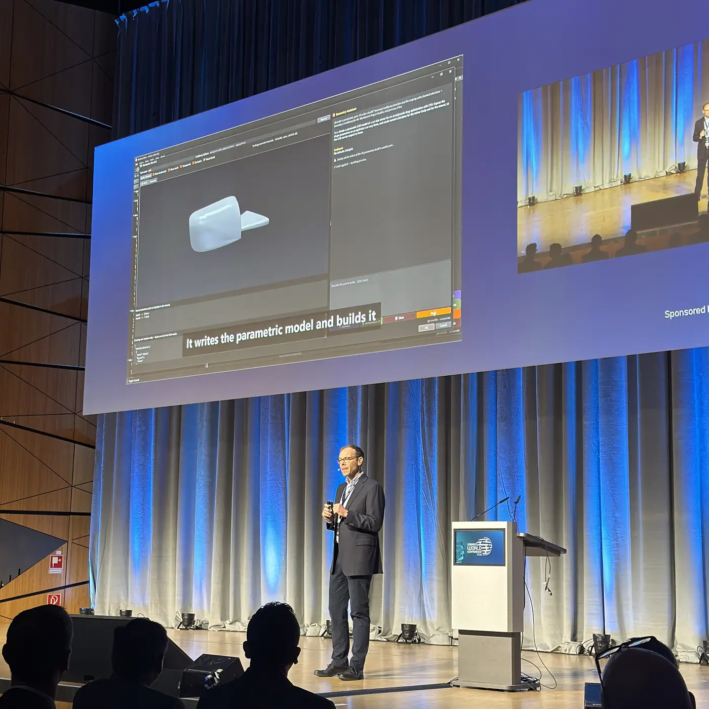 The big screen during the opening keynote shows an AI assistant window with a 3D car mirror model and the subtitle It writes the parametric model and builds it.