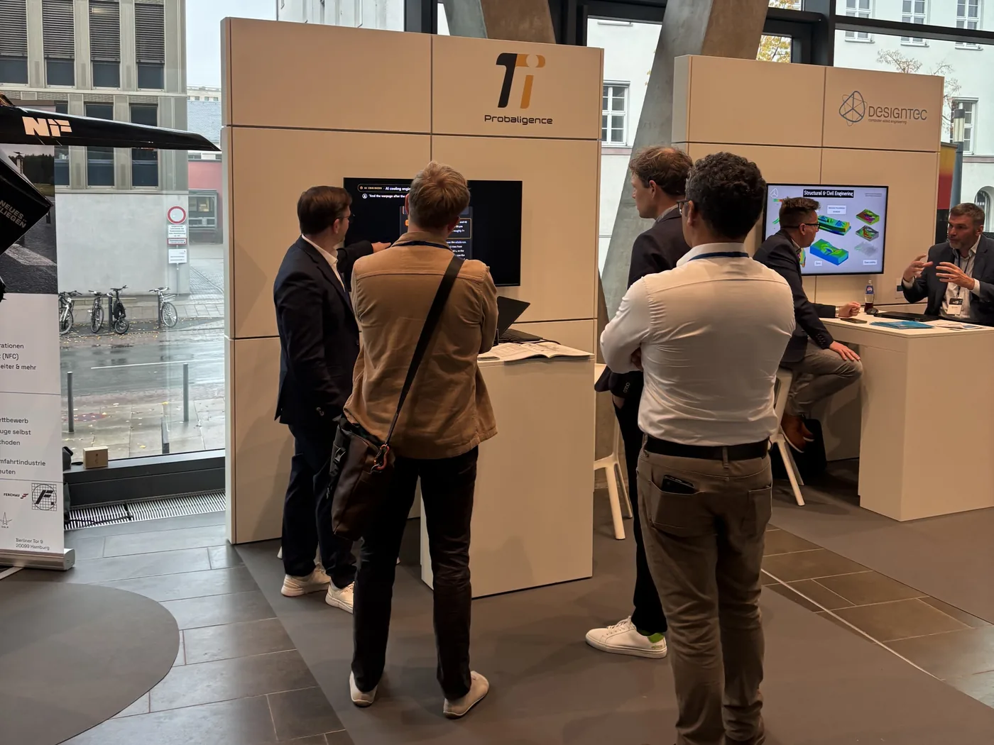 Two visitors at the PI Probaligence booth watching an AI agent demo on the screen, with a neighboring booth on the right.