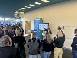 Visitors gathered around the Na, Logisch stand watching a screen presentation during the exhibition